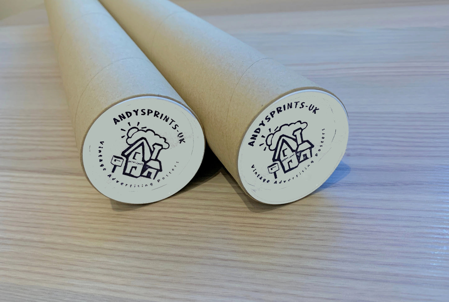 Two sturdy postal tubes with 'Andy's Prints UK' logo on a light wooden surface